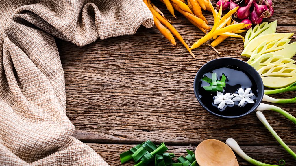 Fresh Asian herbs, lemongrass, chilli and spices laid out on a wooden table for cooking