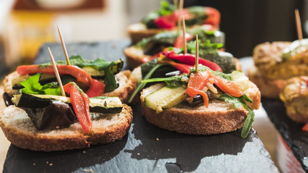A spread of Basque pintxos, small tapas served on bread, laid out along a bar counter