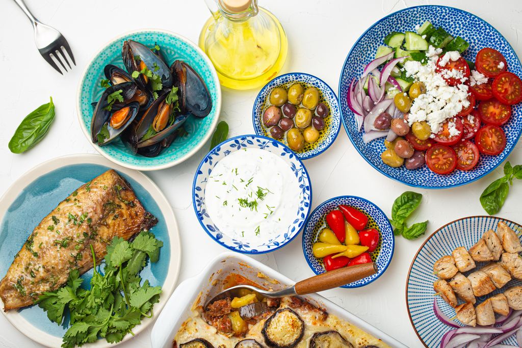 Greek table spread with moussaka, grilled fish, souvlaki, salad and mezze seen from above
