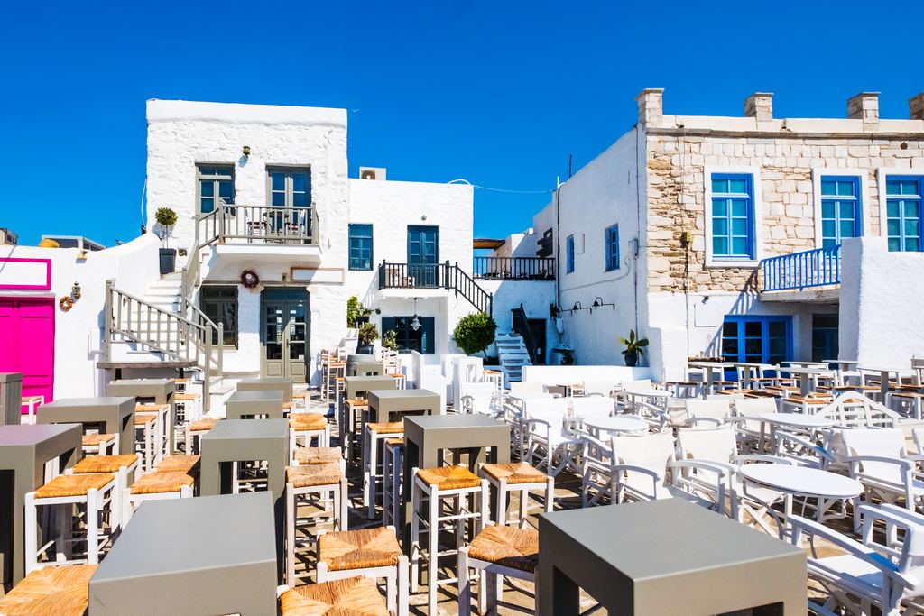 Typical Greek taverna with brightly coloured tables and chairs set out along the waterfront