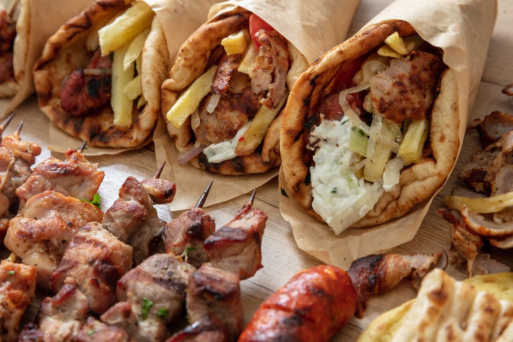 Greek street food: gyros wrapped in pita bread next to a souvlaki skewer, seen from above