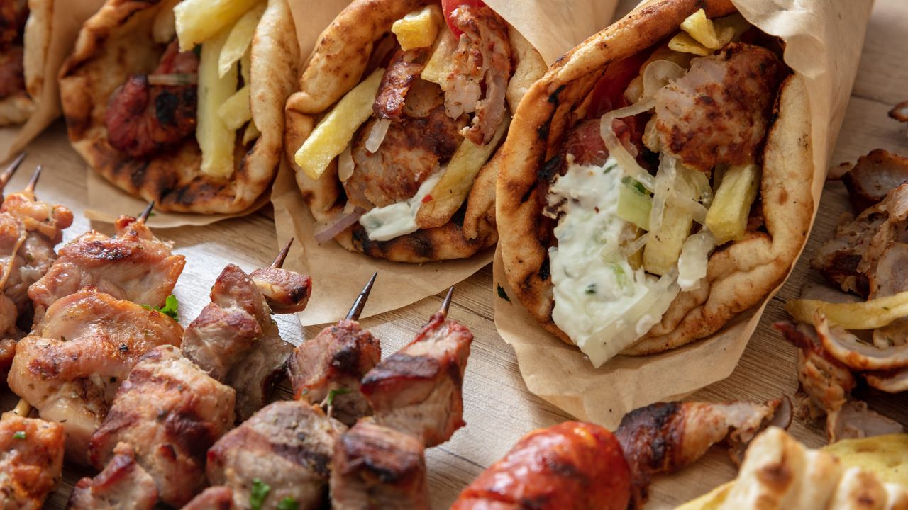 Greek street food: gyros wrapped in pita bread next to a souvlaki skewer, seen from above