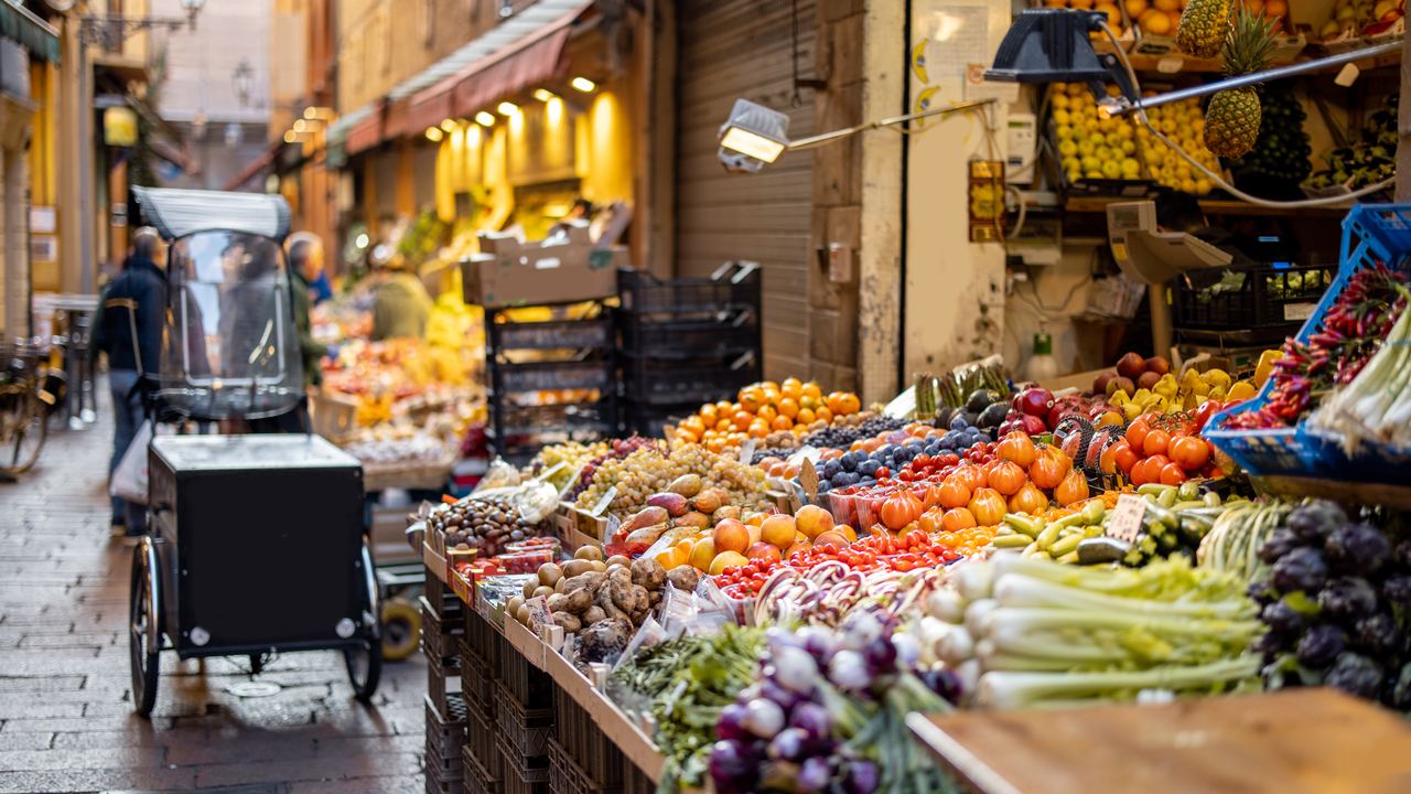 Italian street market stalls piled with fresh local fruit and vegetables