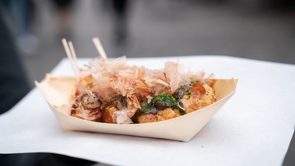 Freshly cooked takoyaki octopus balls in a paper tray topped with bonito flakes