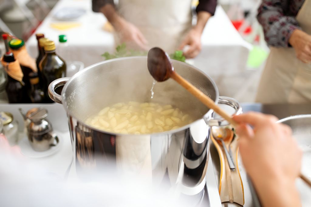 Chef teaching a group how to make pasta during a hands-on cooking class