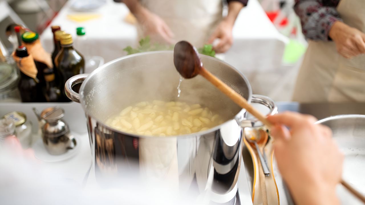 Chef teaching a group how to make pasta during a hands-on cooking class