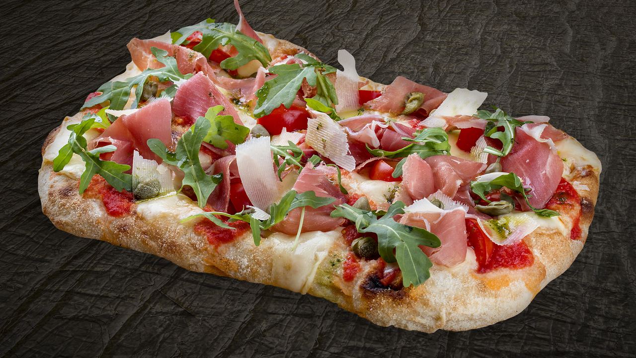 Roman-style rectangular pizza al taglio topped with prosciutto, rocket and capers