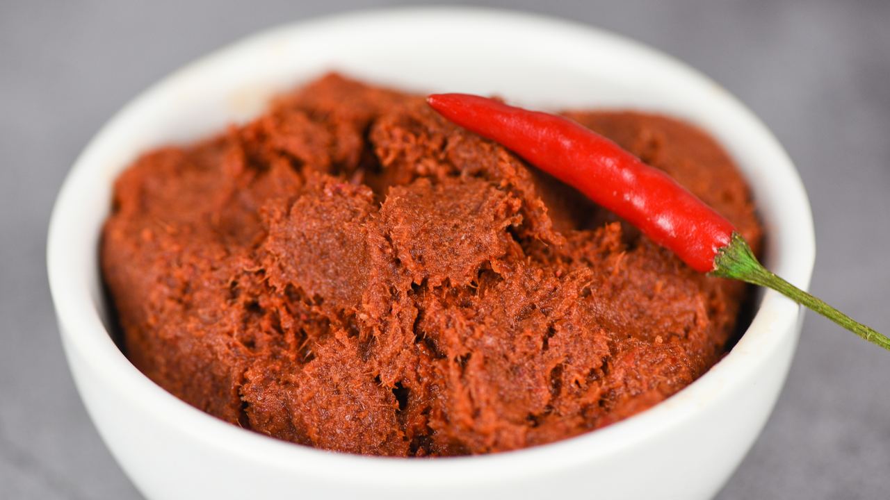 Thai curry paste with red chillies and fresh ingredients laid out on a table