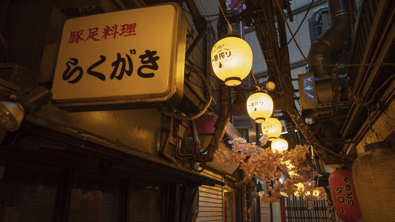 Japanese street of small izakaya bars hung with glowing paper lanterns at night
