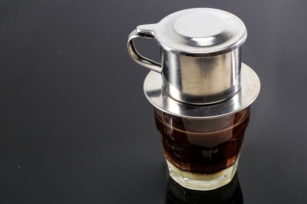 Vietnamese coffee with condensed milk in glass cups beside a traditional phin drip filter